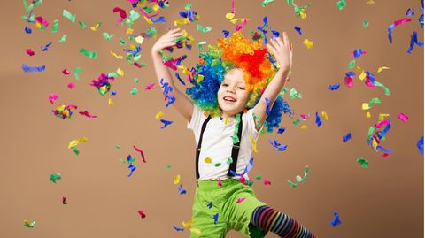 Carnival games for children: boys in clown costumes play with colorful pieces of paper