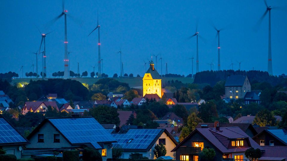 Small town at dusk with solar roofs and wind farm