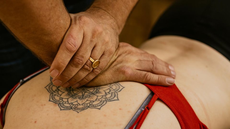 Men's hands massaging a tattooed back