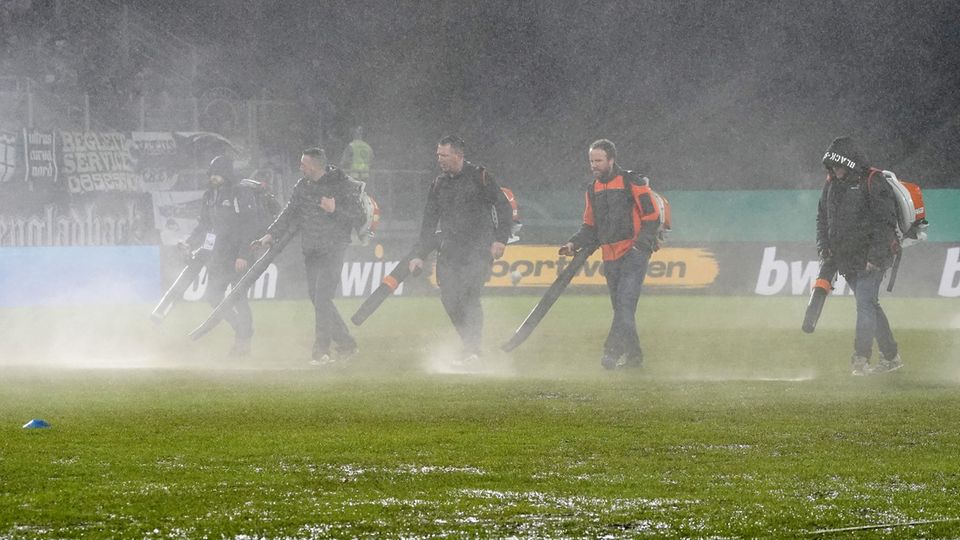 DFB Cup: Helpers use leaf blowers to try to get water from the lawn in Saarbrücken