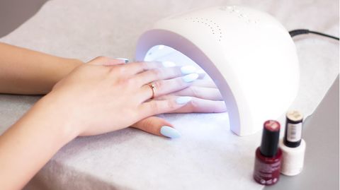 Woman hardens UV nail polish under a nail hardener